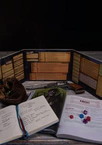 Spire book, notepad, dice with pouch, gun and GM screen on a white wooden table ready to play © SHAW STUDIO