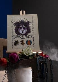 Book of Masks a Spire sourcebook on a cinder block with chains, flowers and smoke © SHAW STUDIO