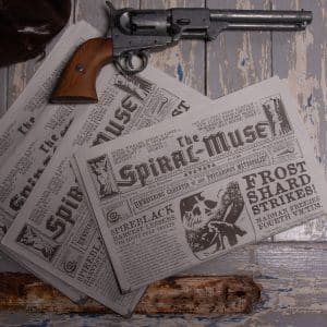 The Spiral Muse newspaper for Spire against a white wood background with a gun and coin pouch © SHAW STUDIO