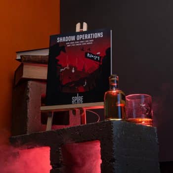 Shadow Operations book for Spire on cinder blocks with books, alcohol and smoke with red lighting © SHAW STUDIO