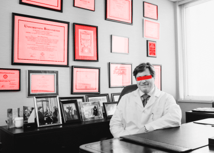 A doctor in an expensive office, its walls covered in diplomas. The doctor is grinning but his eyes are obscured by a slash of red paint.